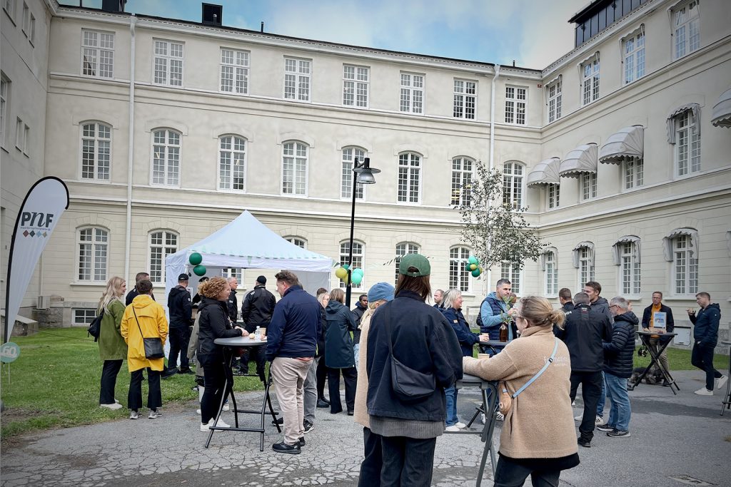 Bilden visar människor som står runt småbord, de samtalar och äter.